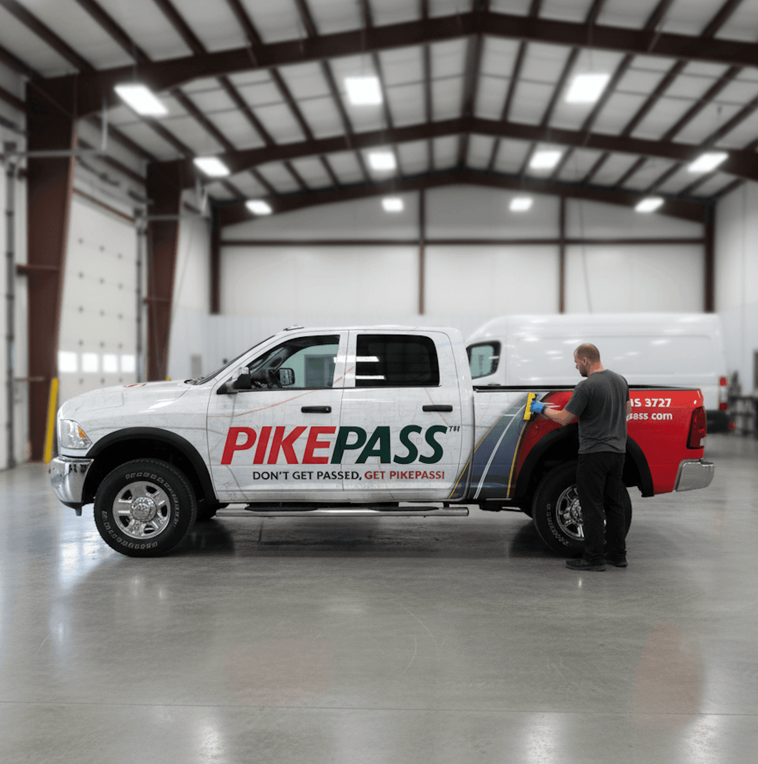 Professional installer applying a PikePass fleet vehicle wrap in a clean Oklahoma wrap shop, ensuring a seamless and precise fit.